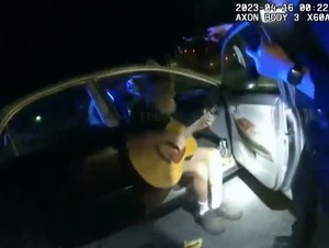 Man pulls out a guitar and serenades officers with his rendition of the John Denver classic